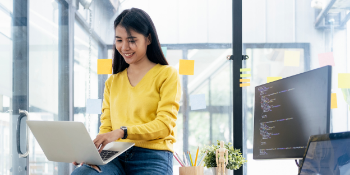 Woman sitting at the edge of her desk, coding on her laptop. Woman sitting at the edge of her desk, coding on her laptop.