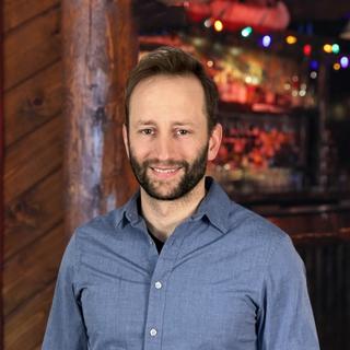 The author in front of a log cabin with soft, warm lighting