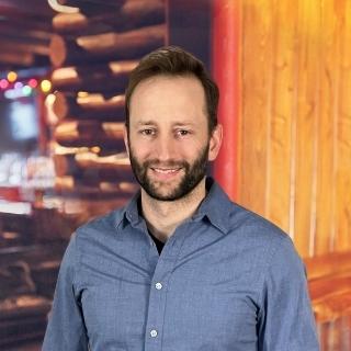 Edward Kozlowski standing in a log cabin interior with soft, warm lighting.